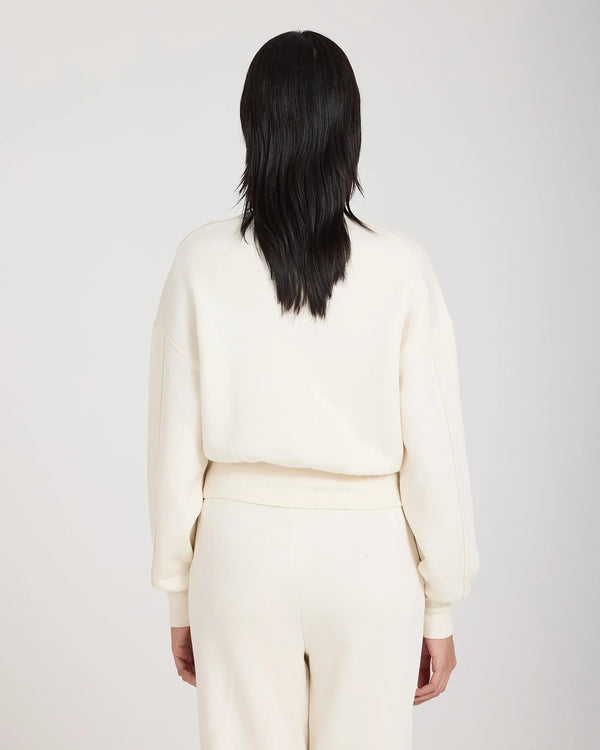 Back view of a cream sweatshirt with debossing, worn by a model, showcasing the relaxed fit and soft lyocell material.