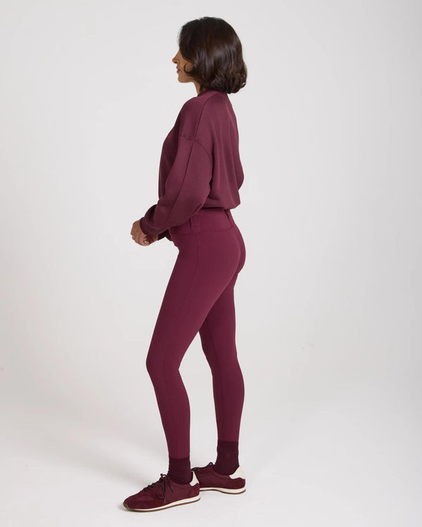 Side profile of model wearing Emello's purple leggings with belt loops, showcasing a form-fitting silhouette.