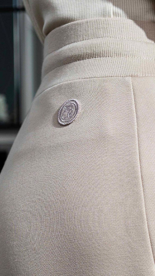 Person wearing beige pants with a close-up of the waistband and pocket.