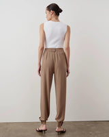 Back view of model wearing Emello Balloon Popper Trousers in taupe, showcasing a fluid, relaxed fit.
