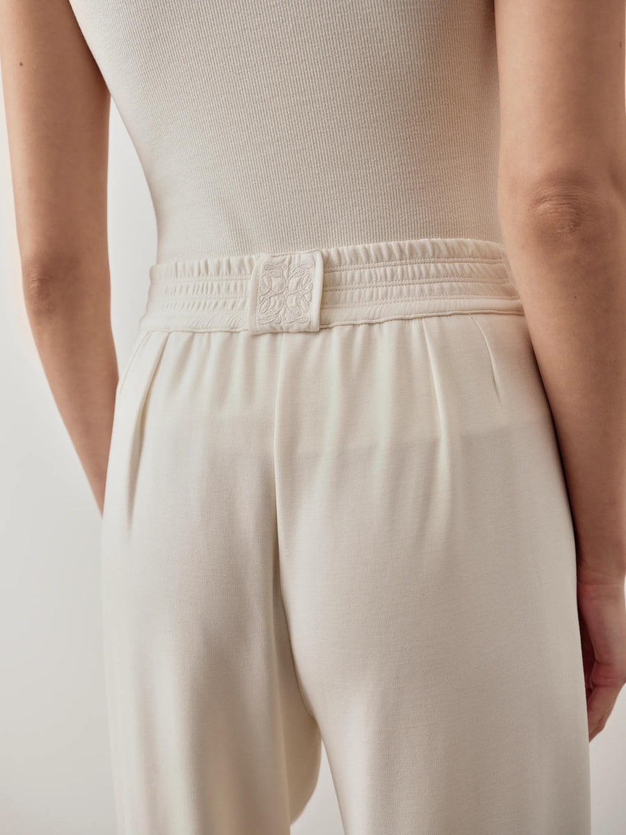 Back view of cream balloon popper trousers showcasing refined waistband detail.