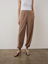Model wearing Emello Balloon Popper Trousers in brown, showcasing a refined balloon silhouette with adjustable popper hems.