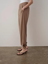 Brown balloon popper trousers with a relaxed fit, featuring a fluid silhouette and adjustable hem poppers.