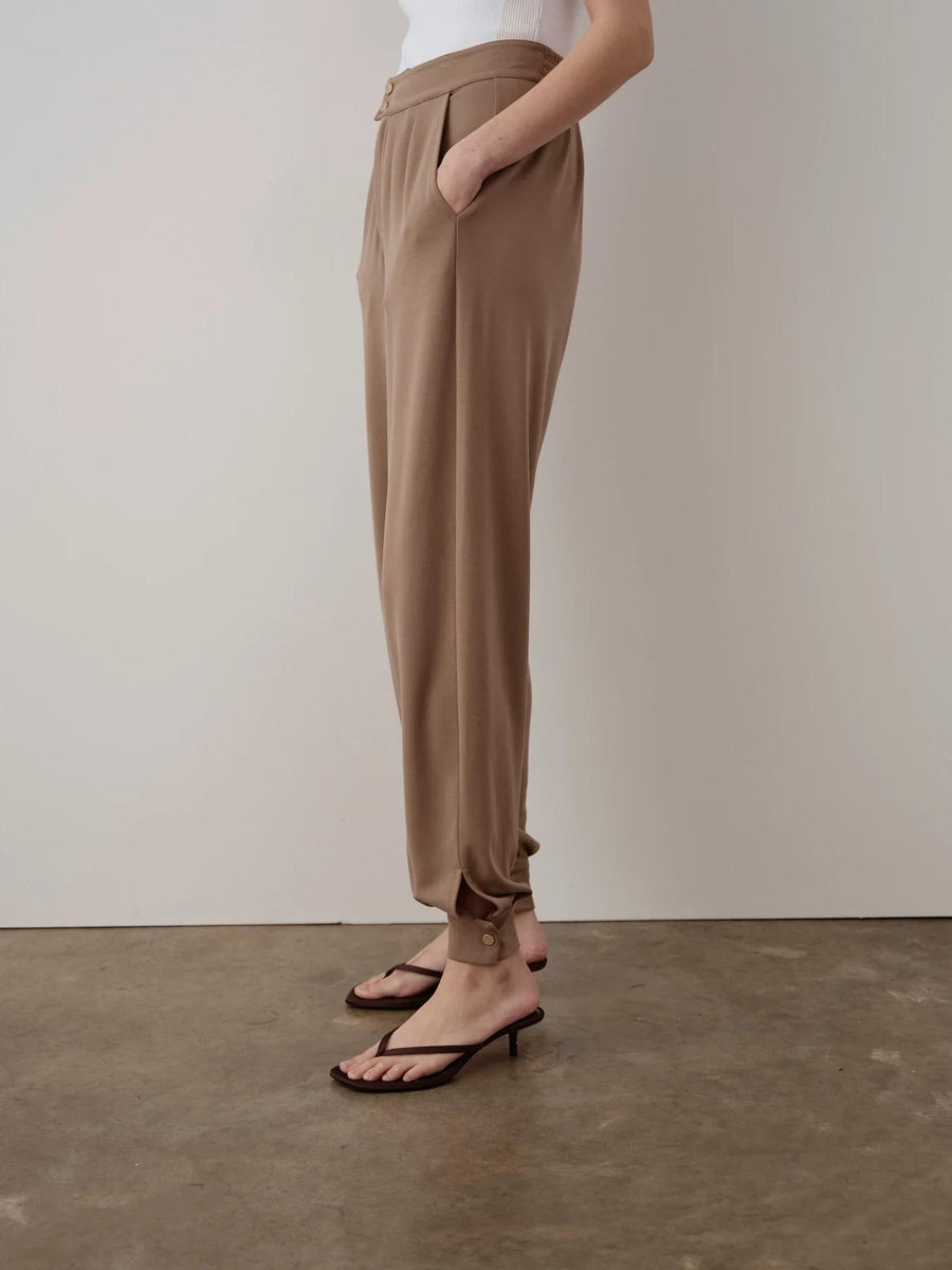 Brown balloon popper trousers with a relaxed fit, featuring a fluid silhouette and adjustable hem poppers.
