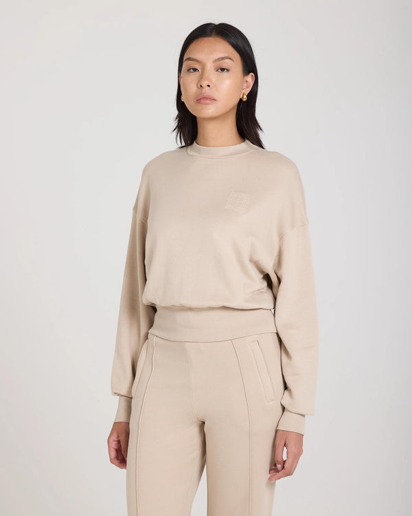 Emello beige Lyocell fleece sweatshirt with debossed logo, worn by a model, featuring a relaxed fit and drop shoulders.