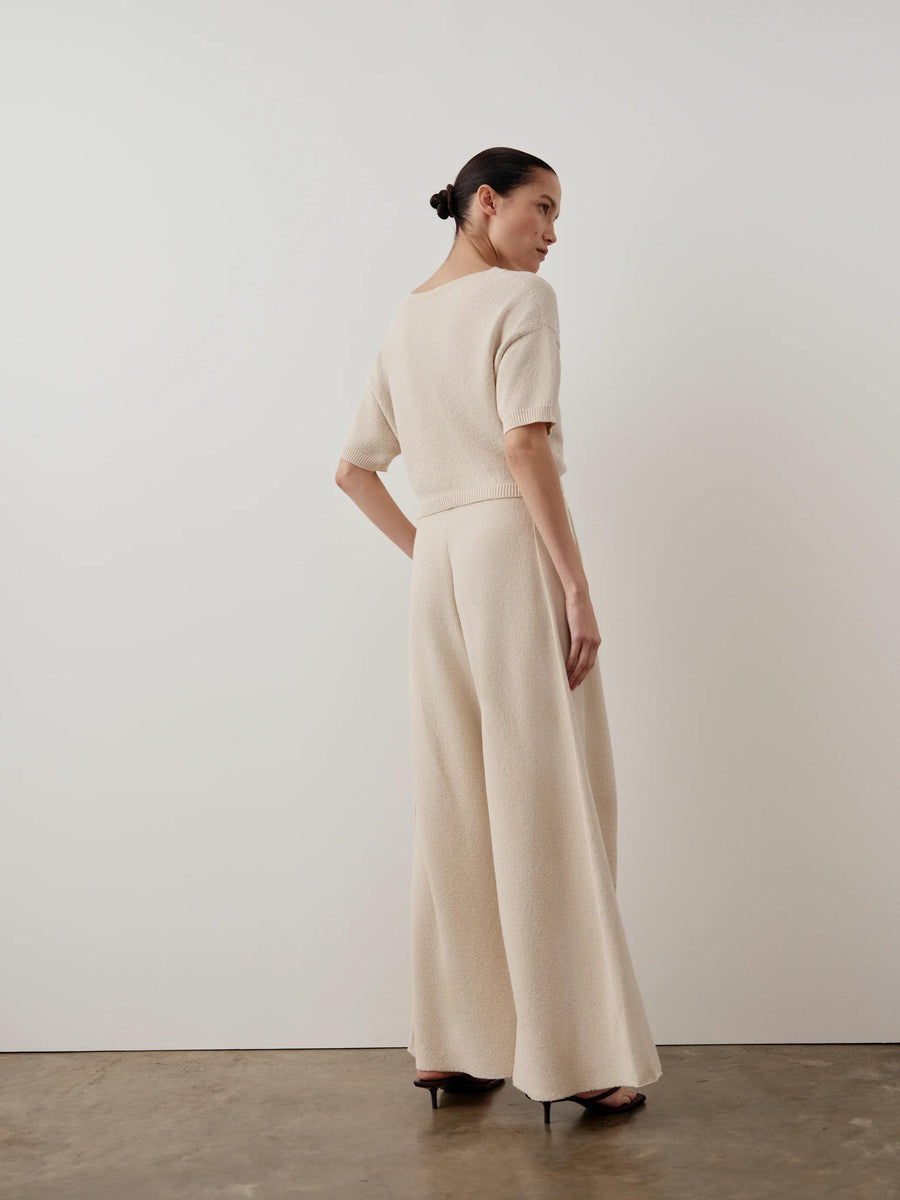 Model wearing Emello Bouclé Wide Leg Trousers in cream, showcasing a fluid drape and softly textured elegance.