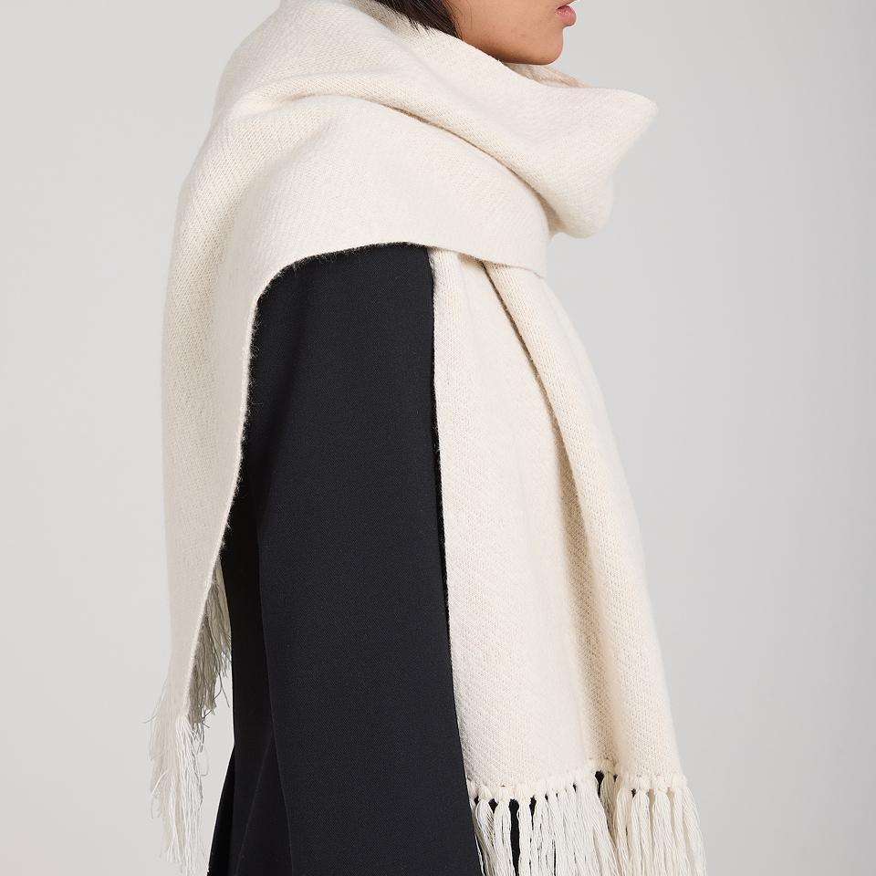 Close-up of a cream brushed alpaca scarf draped over a dark wool coat