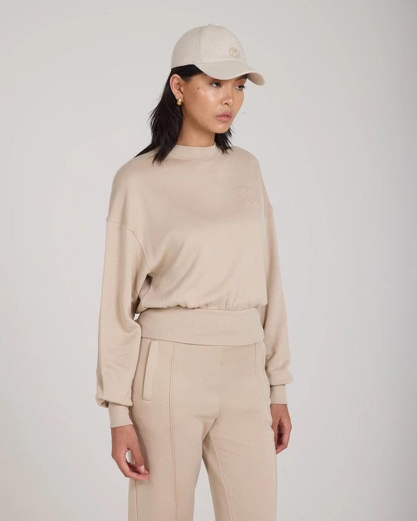Emello Cap in beige brushed cotton twill with pale gold disc embellishment, worn by model.