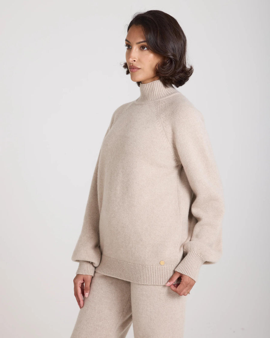 Kasima Cashmere Blend Knit Sweater in beige, showcasing its relaxed fit and folded rib funnel neck.