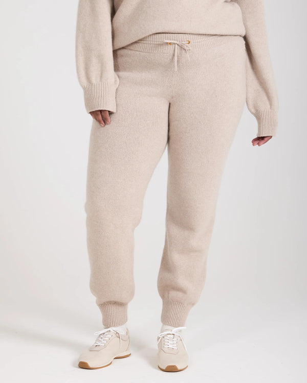 Kasima Cashmere Blend Knit Trousers in Beige with ribbed details, worn with sneakers.