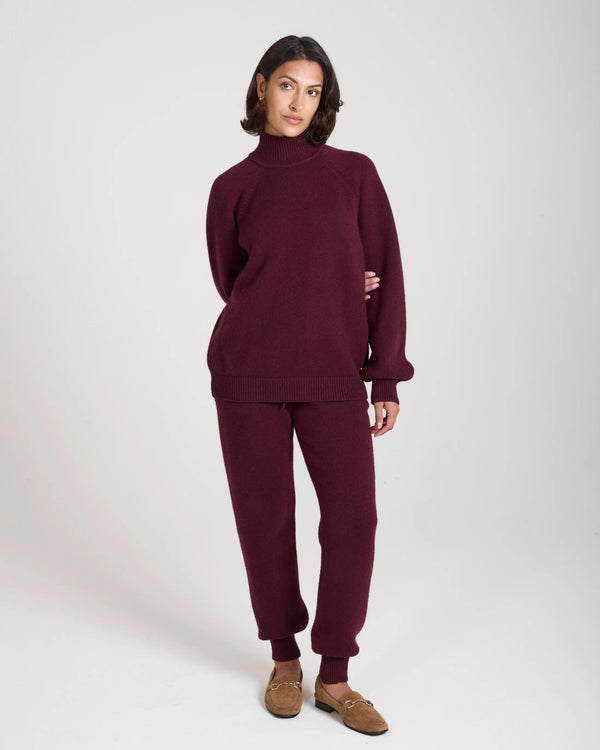 Model wearing Emello Kasima Cashmere Blend Knit Sweater in fig, showcasing a relaxed fit with a folded rib funnel neck.
