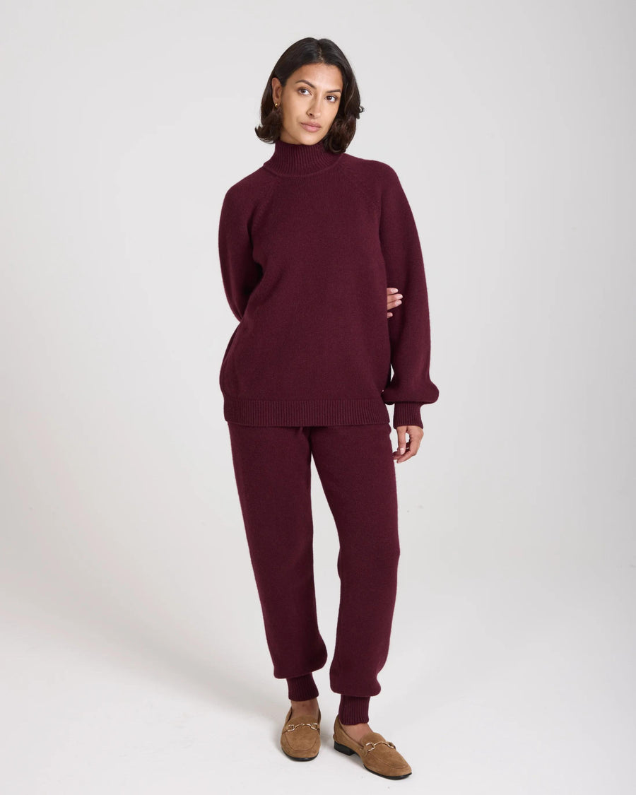 Model wearing Emello Kasima Cashmere Blend Knit Sweater in fig, showcasing a relaxed fit with a folded rib funnel neck.