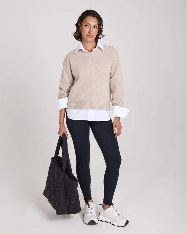 Model wearing Kasima Cashmere Blend V Neck Sweater in beige with relaxed fit and white shirt underneath.