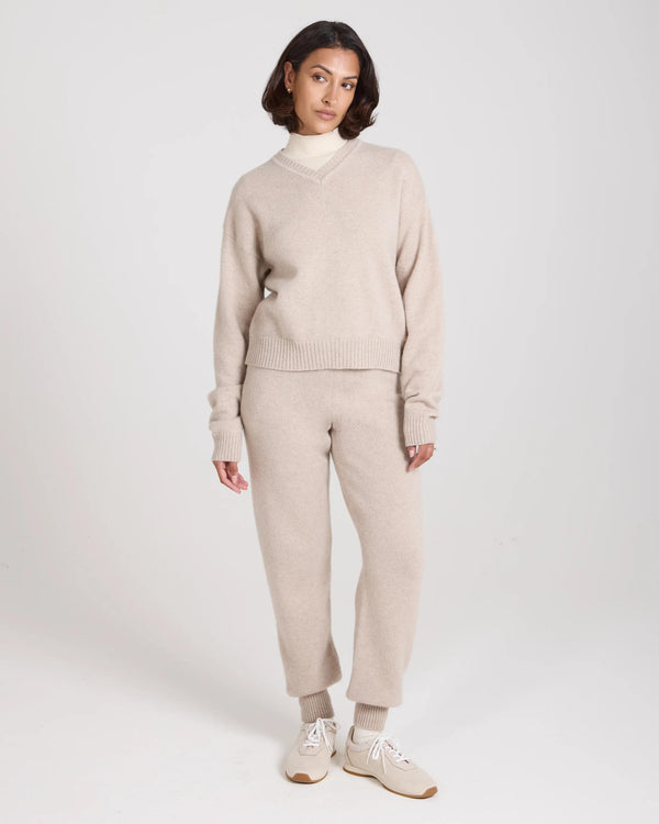 Elegant beige Kasima cashmere blend v-neck sweater worn by model, featuring ribbed texture and relaxed fit.