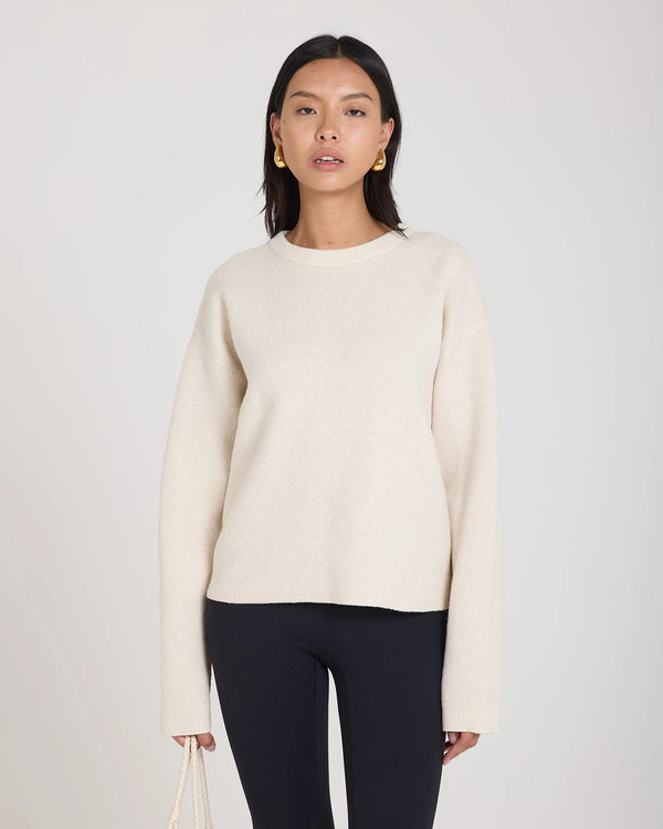 Elegant cream reversible jacquard sweater in a luxurious cashmere blend, showcasing tactile elegance.