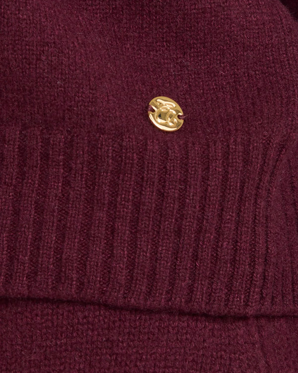 Kasima Cashmere Blend V Neck Sweater in Fig with gold-finish emblem on ribbed texture.