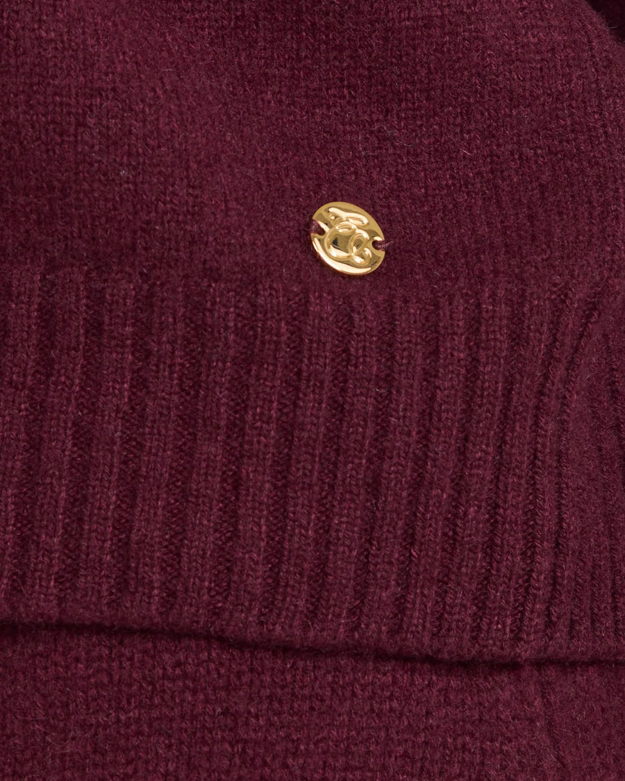 Kasima Cashmere Blend V Neck Sweater in Fig with gold-finish emblem on ribbed texture.