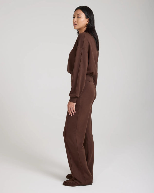 Side-profile view of a model wearing a relaxed chocolate brown lyocell fleece sweatshirt from Emello.