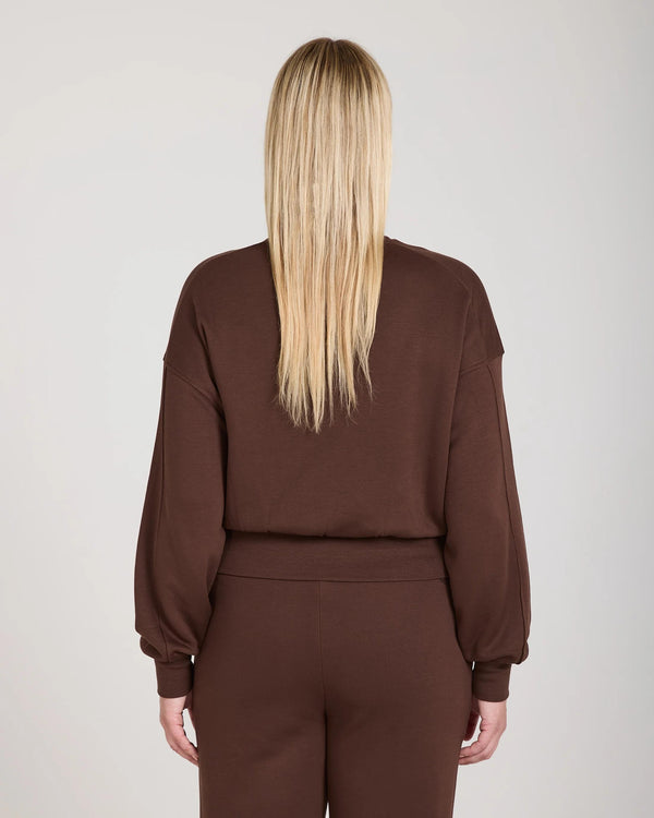Back view of a brown lyocell fleece sweatshirt with a relaxed fit, worn by a model with long hair.