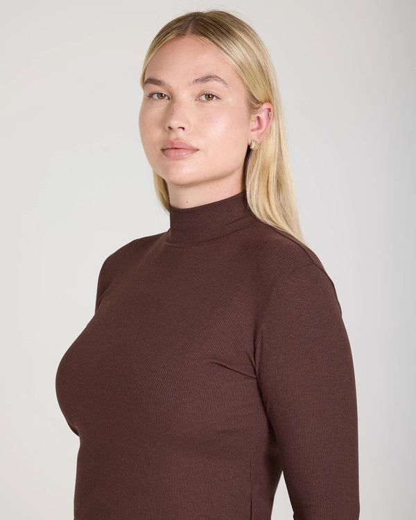 Refined chocolate turtleneck by Emello in ribbed lyocell-cotton, high-collared elegance captured in soft light.