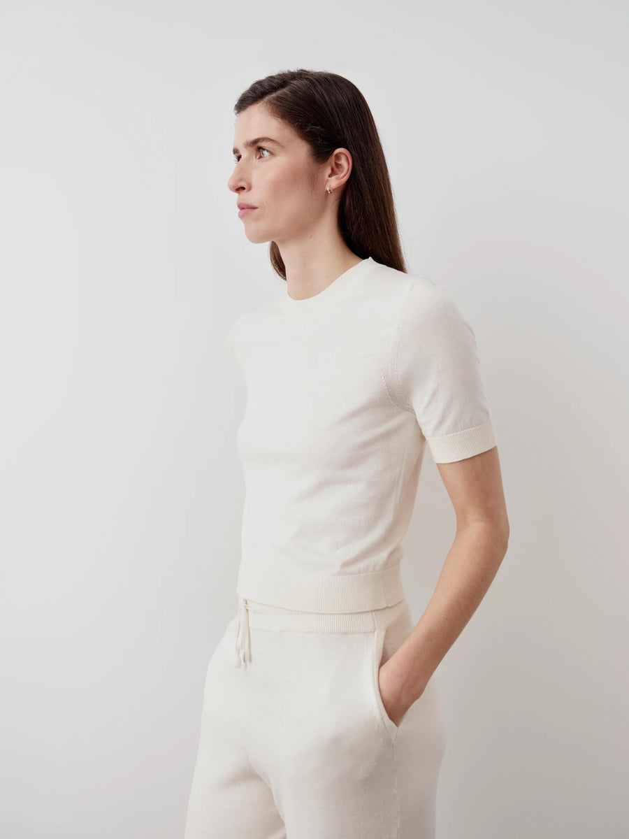 Woman wearing Emello's Cotton Cashmere Knit Tee in cream, showcasing its refined fit and fluid drape.