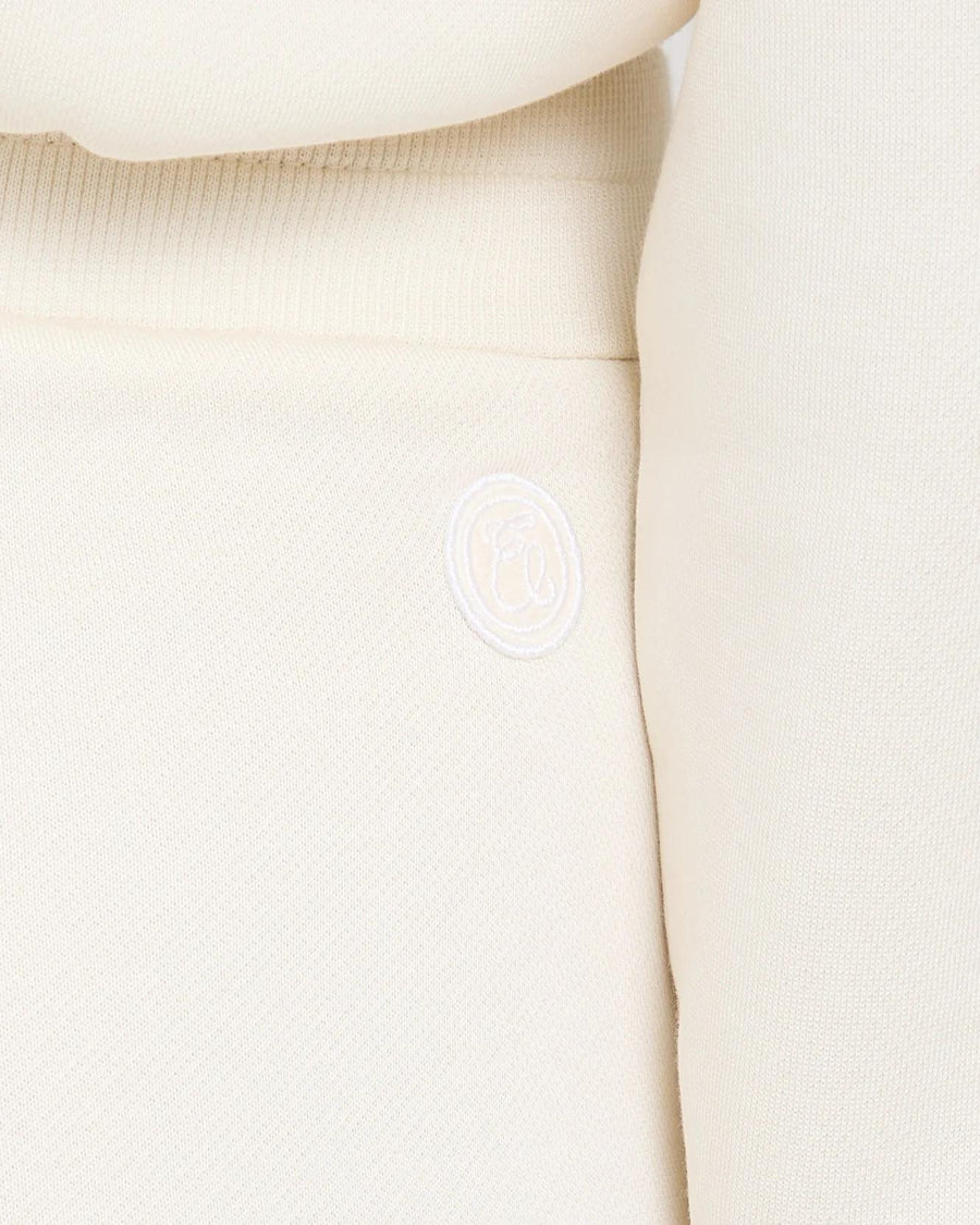 Close-up of cream cuffed trousers with Emello's logo embroidery, showcasing brushed lyocell texture.