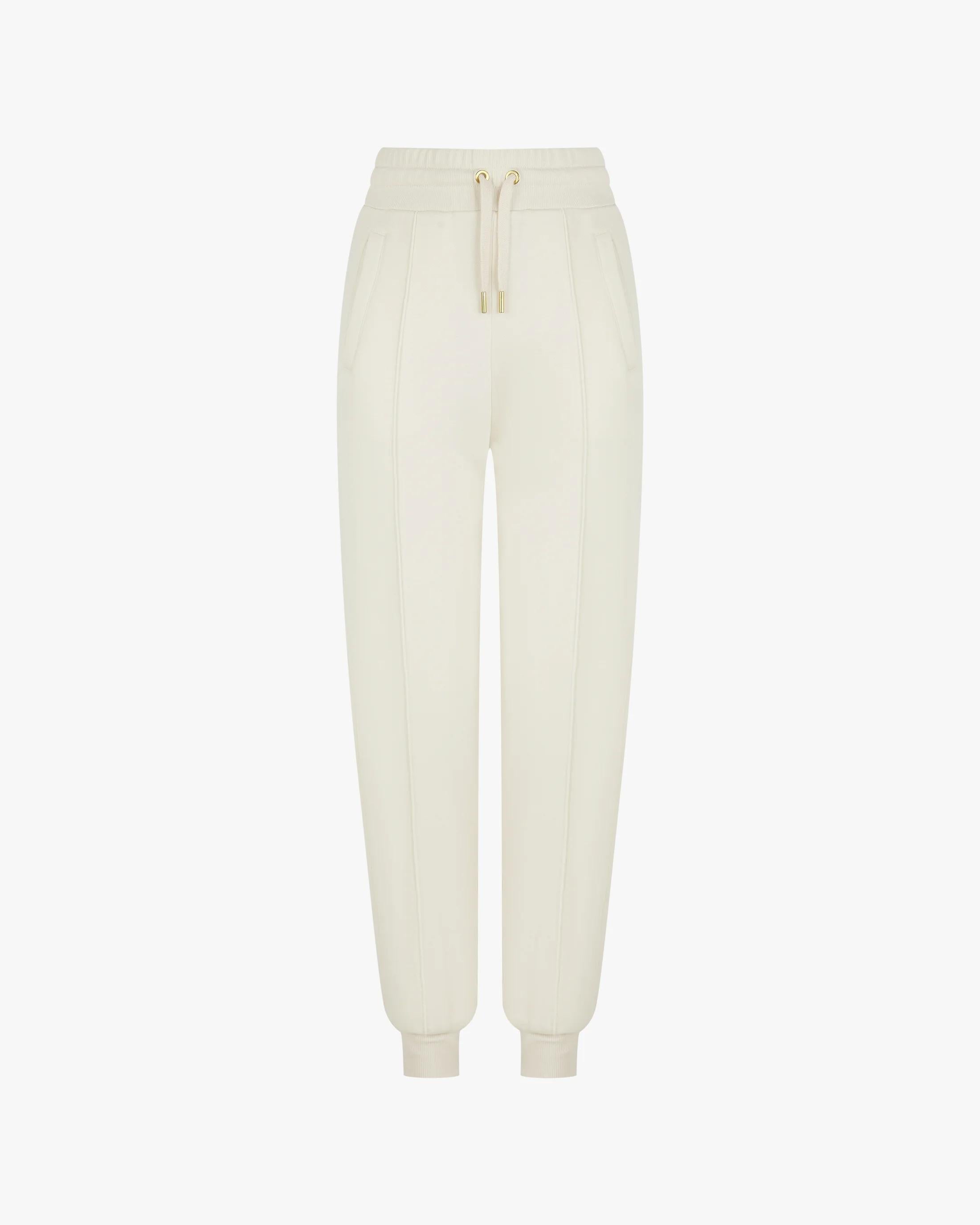 Cream cuffed trousers in brushed lyocell fleece with gold hardware and pockets, featuring refined pin-tuck detailing.