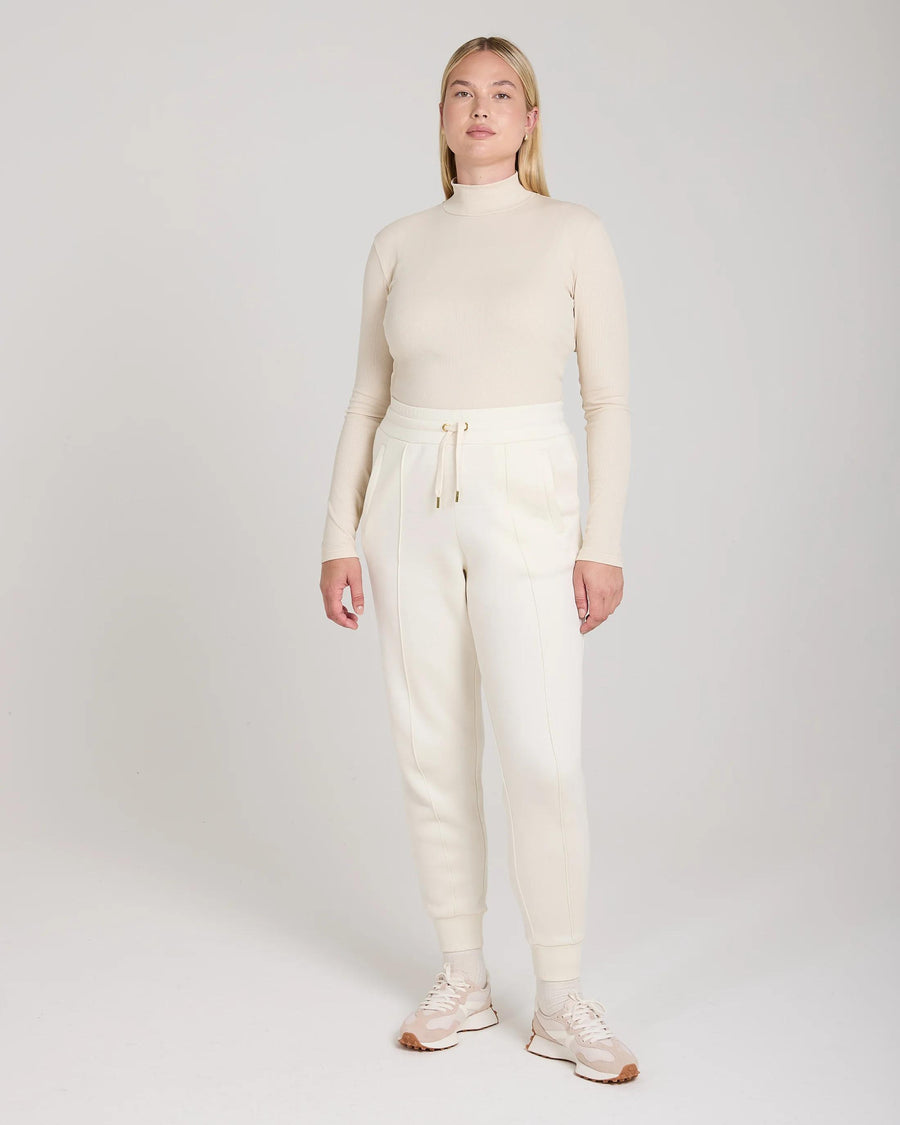 Emello Cuffed Trouser in cream lyocell, showcasing elegant pin-tuck detailing and gold hardware.