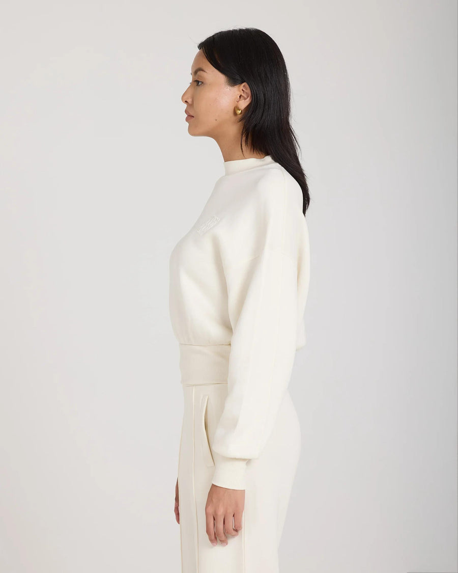 Side profile of a cream lyocell sweatshirt with debossing worn by a model, displaying relaxed fit and ribbed detailing.