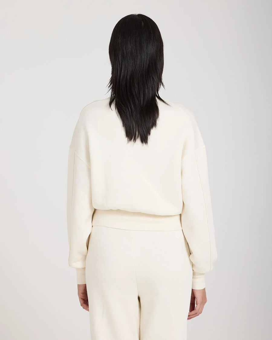 Back view of a cream sweatshirt with debossing, worn by a model, showcasing the relaxed fit and soft lyocell material.