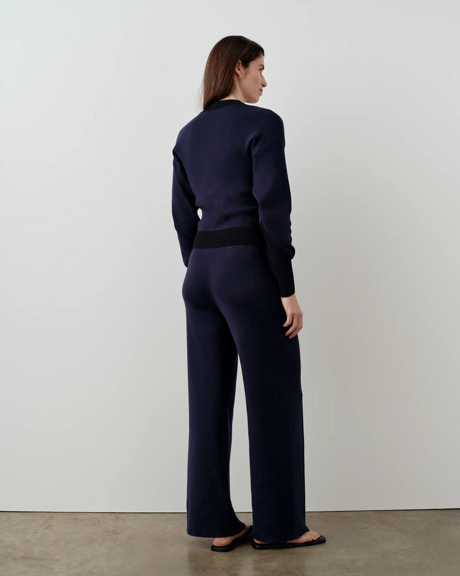 Model wearing Emello navy double waistband knitted trousers, showcasing the smooth silhouette and refined drape.