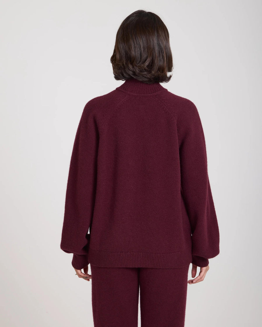 Back view of a burgundy cashmere blend sweater with funnel neck, worn by a model.