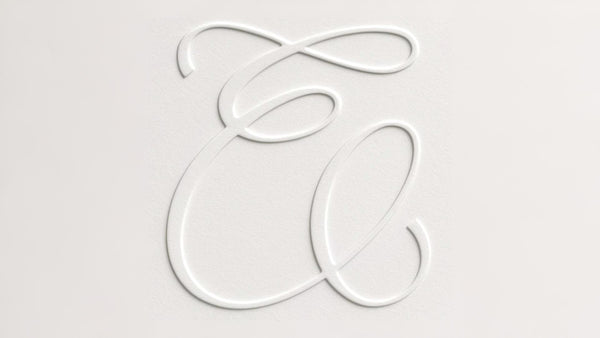 Subtly embossed Emello monogram on softly textured white paper backdrop