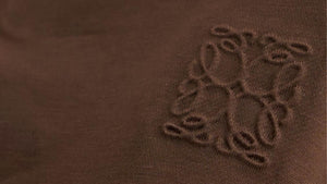 Close-up of tonal brown embroidery on fine-gauge knit fabric