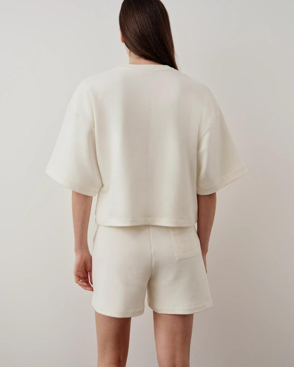 Back view of cream embroidered pocket shorts made from midweight French terry, showcasing relaxed fit and signature back pocket embroidery.