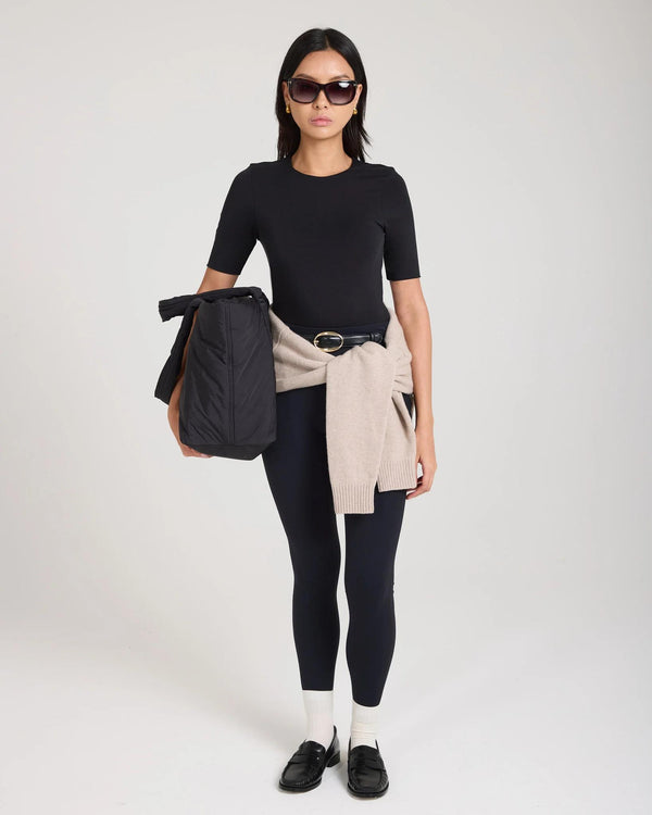 Elegant woman wearing Emello Forma Silky Lyocell Jersey Double-Layer Top in black, styled with sunglasses and casual attire.