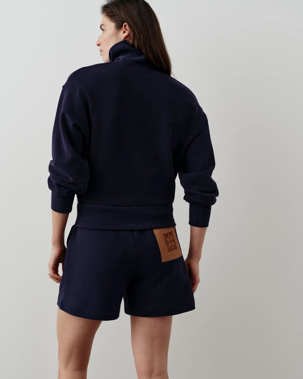 Back view of a navy half-zip funnel-neck sweatshirt with voluminous sleeves and softly structured rib hem worn by a model.
