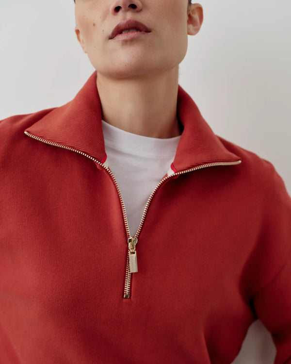 Rust red half-zip funnel-neck sweatshirt with a blouson silhouette, highlighting refined and tactile elegance.