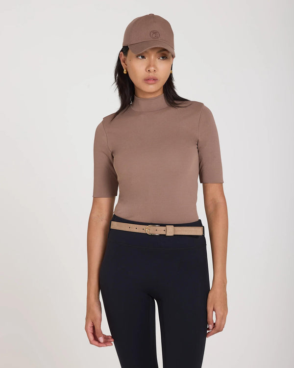 Model wearing Emello's Double Layer High Neck Top in taupe viscose, paired with black leggings and a taupe cap.