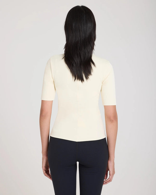Back view of Emello's cream double layer high neck top in viscose, worn by model.