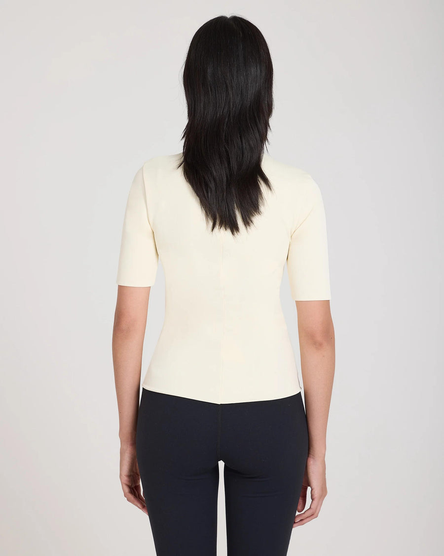 Back view of Emello's cream double layer high neck top in viscose, worn by model.