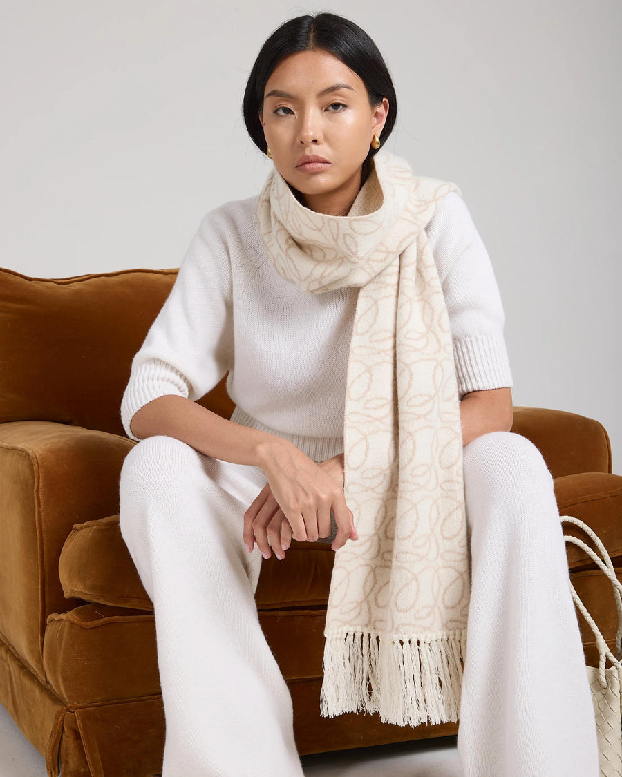 Jacquard cream cashmere scarf styled with fringed tassels, draped elegantly.