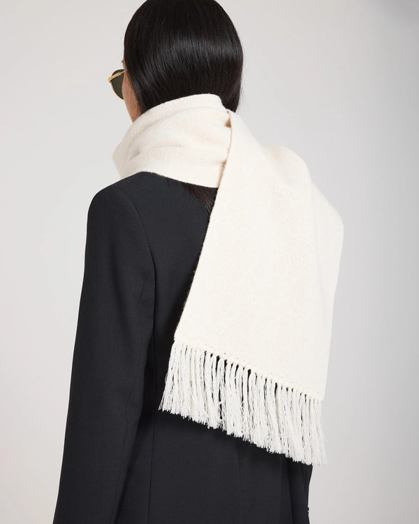 Elegant cream jacquard cashmere scarf draped over shoulder with fringed tassels.