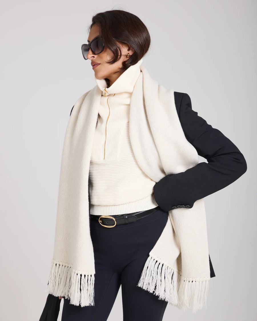 Elegant woman wearing a cream jacquard cashmere scarf with fringed tassels, styled with a black blazer and sunglasses.