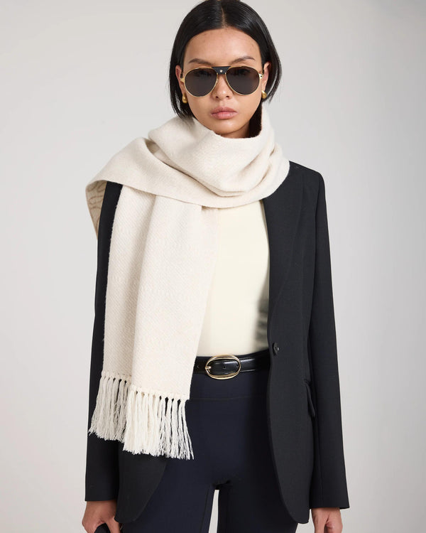 Cream jacquard scarf in brushed cashmere with fringed tassels, elegantly draped over a black blazer.