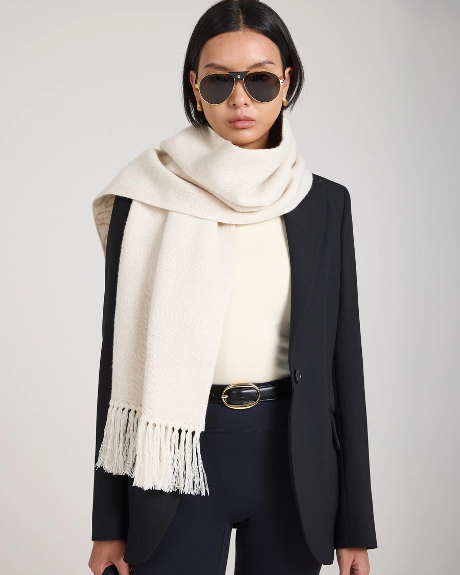 Cream jacquard scarf in brushed cashmere with fringed tassels, elegantly draped over a black blazer.