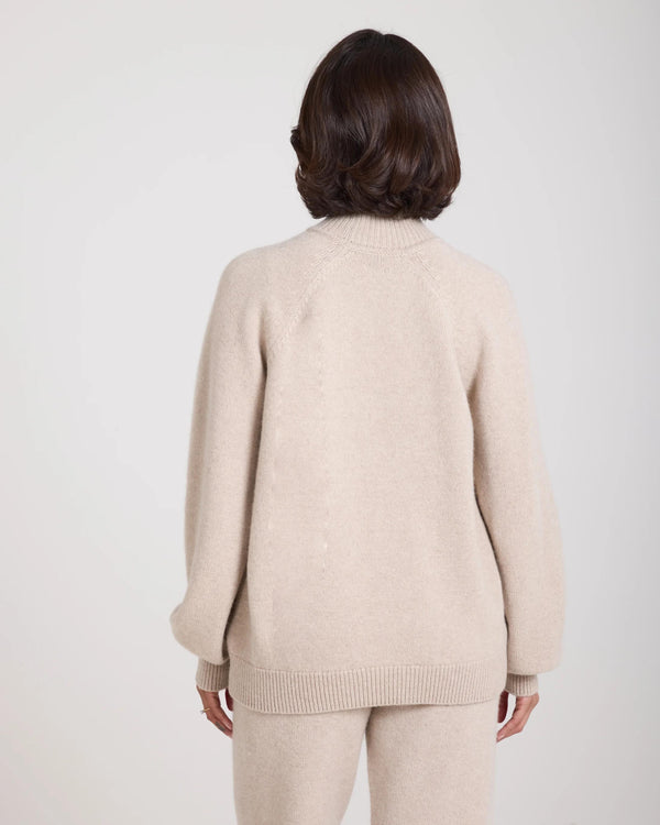 Back view of Kasima Cashmere Blend Knit Sweater in beige, showcasing its relaxed fit and ribbed funnel neck.