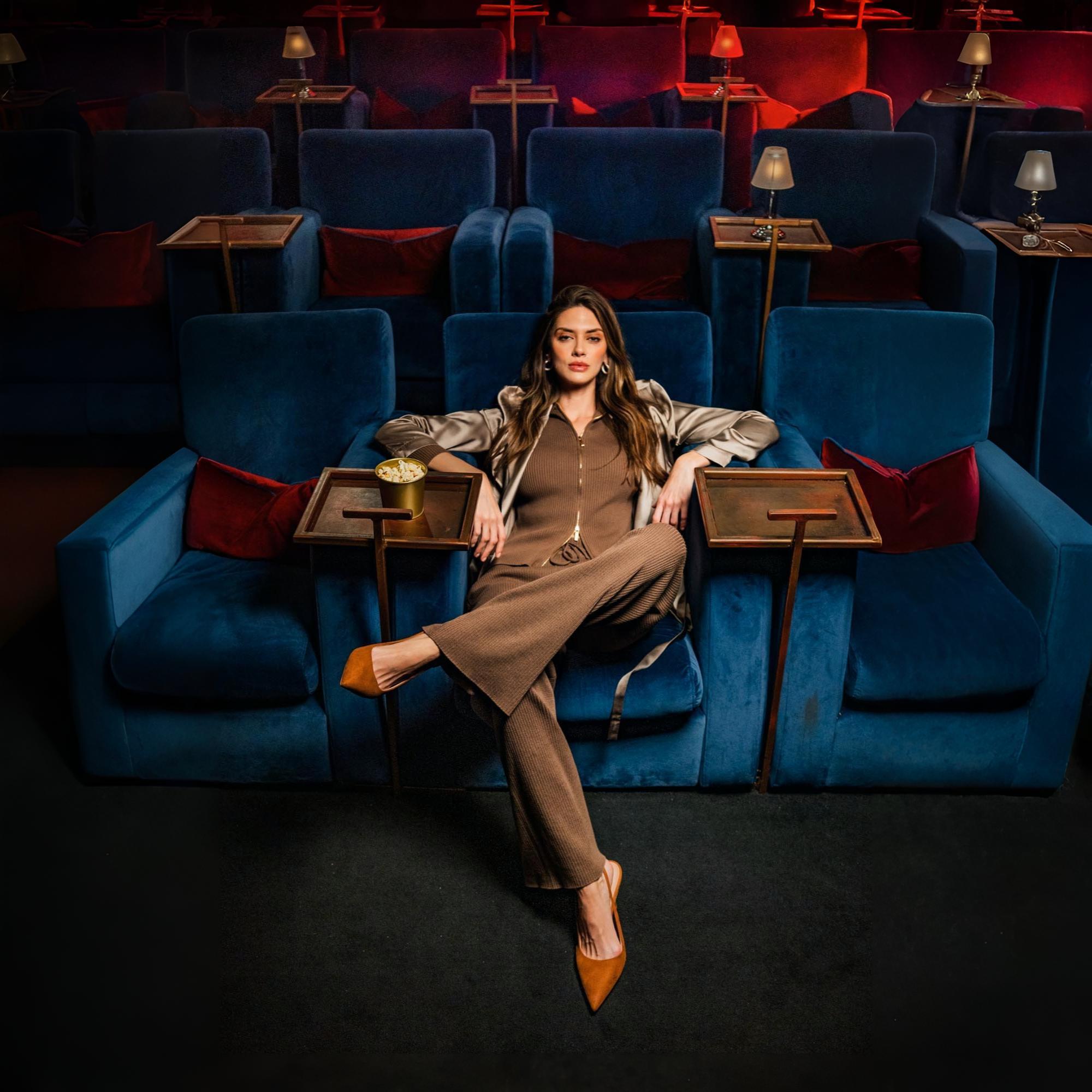 Woman in brown ribbed knitwear lounging in a velvet cinema seat