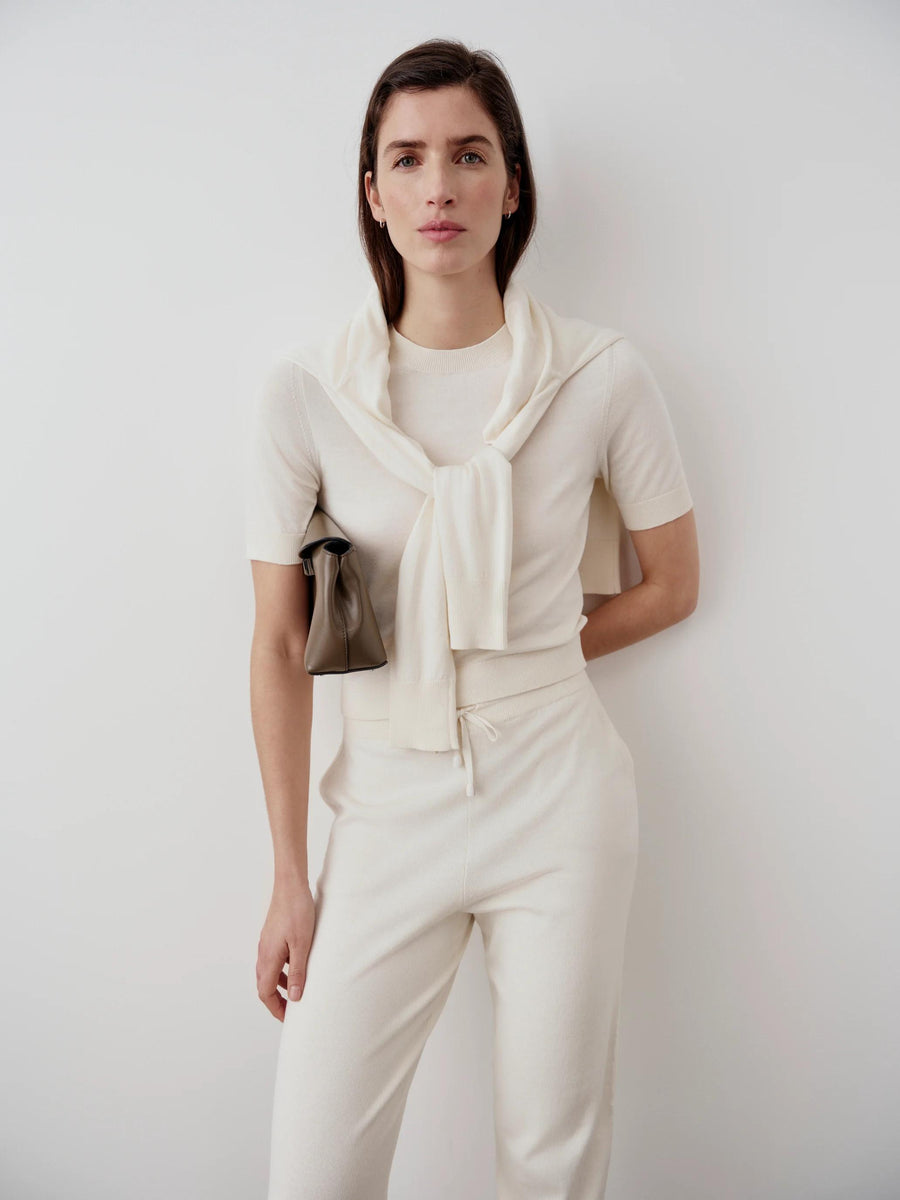 Model wearing Emello Cotton Cashmere Knit Tee in Cream, paired with matching trousers, embodying refined elegance.