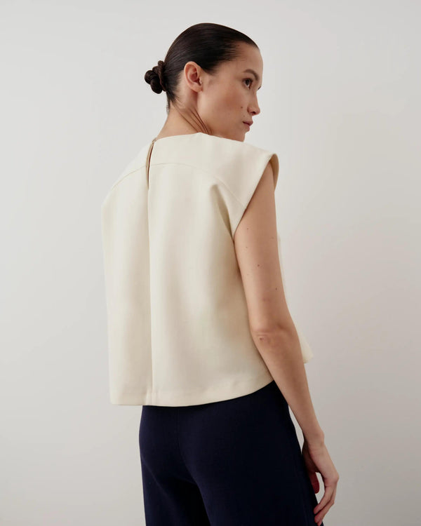 Model wearing Emello structured layered vest in cream, showing clean architectural lines and soft silhouette.